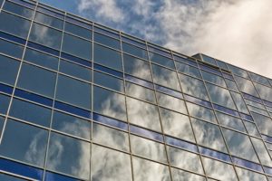 An image of a commercial building with clouds reflecting on the windows.